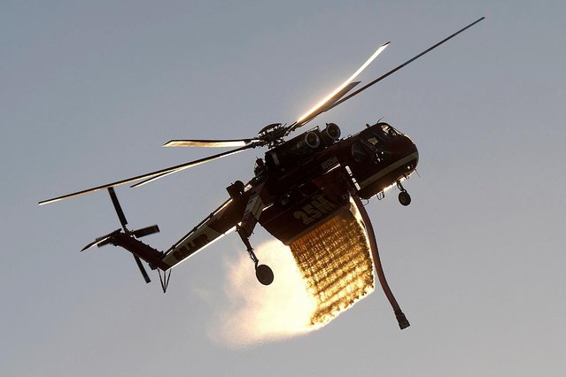 A helicopter drops water while battling the Mountain Fire along Waters Road in Moorpark, Calif., on Thursday, November 7, 2024. (Photo by Noah Berger/AP Photo)