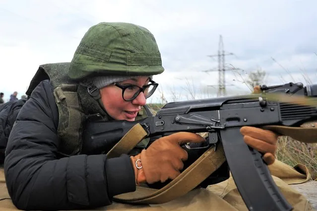 A woman prepares to fire from a Kalashnikov assault rifle at short-term courses where everyone can be able to receive military skills during theoretical and practical training is provided at a military range in Rostov-on-Don region, southern Russia, Friday, October 21, 2022. (Photo by AP Photo/Stringer)