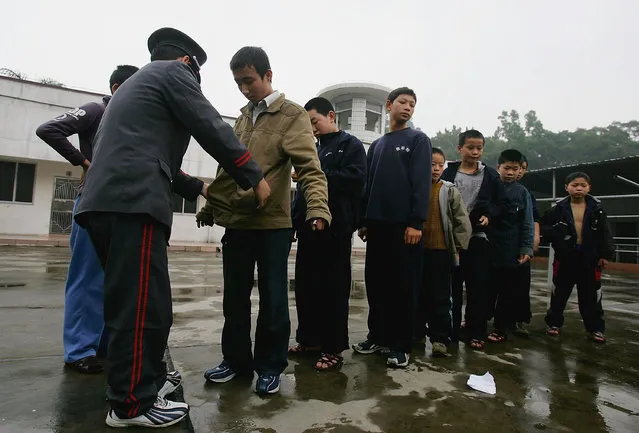 A security guard frisks boys after one kid's money was stolen at an assistance center February 24, 2005 in Shenzhen, Guangdong Province, China. (Photo by Cancan Chu/Getty Images)
