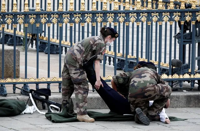 French soldiers help a soldier at unease during the Bastille Day celebrations on Place de la Concorde in Paris, France, July 14, 2020. (Photo by Benoit Tessier/Reuters)