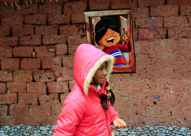 A girl walks pass the facade of a replica of the house where Bolivia's President Evo Morales was born, as it is presented by the government as “The House of Desires”, during the Christmas season at the Murillo square in La Paz, Bolivia, December 8, 2017. (Photo by David Mercado/Reuters)