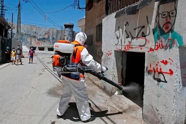 A worker of the Palestinian Bethlehem municipality in cooperation with the popular committee of Aida Refugee Camp, dressed in PPE (personal protective equipment), sterilises a street against Covid-19 coronavirus on June 25, 2020 in the Aida Refugee Camp near in the West Bank city of Bethlehem. Coronavirus cases in the West Bank have more than doubled in a week, the Palestinian Authority said after warning a second wave of infections could be worse than the first. (Photo by Musa Al Shaer/AFP Photo)