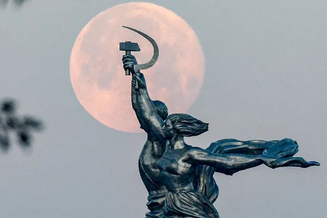 The full moon is pictured behind the sculpture of “Worker and Kolkhoz Woman” in Moscow on July 6, 2020. (Photo by Kirill Kudryavtsev/AFP Photo)