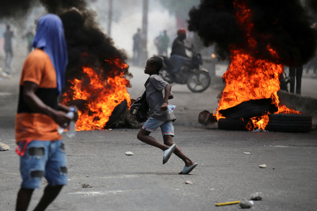A child runs past a burning barricade during a protest against gang-related violence and to demand the resignation of Haiti's transitional presidential council, in Port-au-Prince, Haiti, on March 26, 2025. (Photo by Jean Feguens Regala/Reuters)