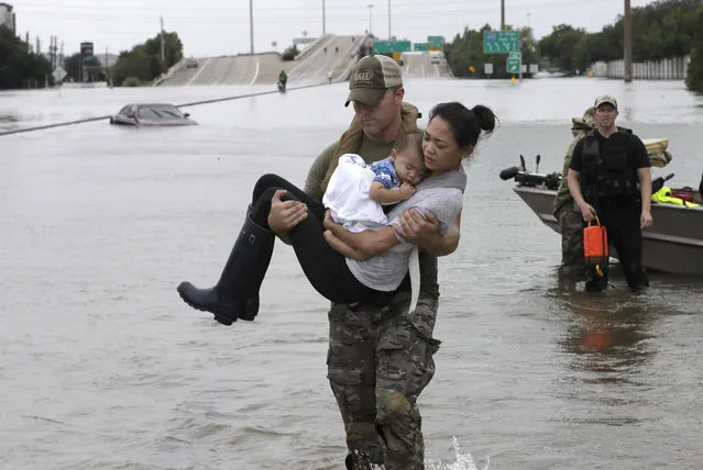 Houston Police SWAT officer Daryl Hudeck carries Catherine Pham and her 13-month-old son Aiden after rescuing them from their home surrounded by floodwaters from Tropical Storm Harvey on August 27, 2017, in Houston. (Photo by David J. Phillip/AP Photo)