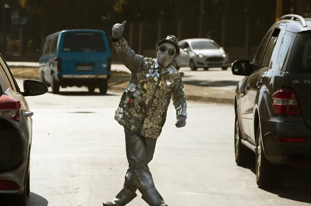 A masked mime artist performs for tips at a busy intersection in Johannesburg, Sunday, August 2, 2020 as the country marks one hundred and twenty nine days days of lockdown to prevent the spread of COVID-19. (Photo by Denis Farrell/AP Photo)
