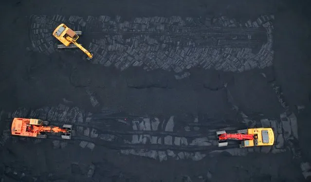 This aerial photo taken on November 28, 2022 shows excavators transferring coal at a port in Lianyungang, in China's eastern Jiangsu province. (Photo by Reuters/China Stringer Network)