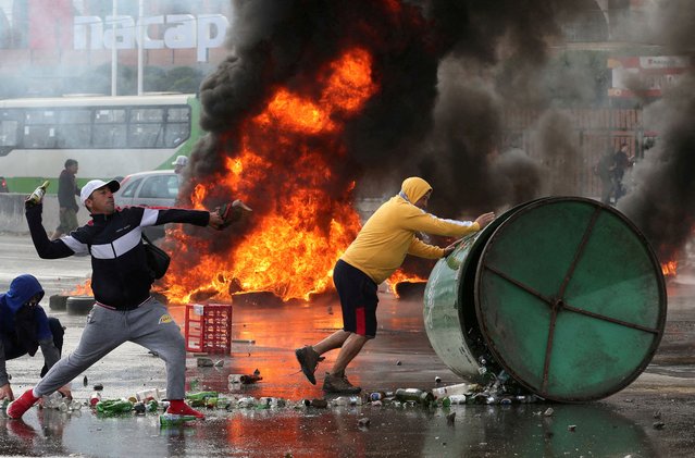 A fire burns as demonstrators clash with riot police, throwing bottles and rolling a bin, during a protest by fishermen against the government, demanding that it approves a new fishing law in the congress in Valparaiso, Chile on March 11, 2025. (Photo by Rodrigo Garrido/Reuters)