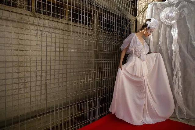 In this Monday, October 27, 2014 photo, a model adjusts her dress before walking a runway for a fashion show in Neve Tirza prison in Ramle, central Israel. Neve Tirza, Israel's only women's prison, hosted its first fashion show Monday where models on towering heels strutted on a red catwalk, showcasing clothes designed and made by inmates. (Photo by Oded Balilty/AP Photo)