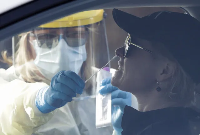 Medical staff take a COVID-19 test from a visitor to a drive through community based assessment centre in Christchurch, New Zealand, Thursday, August 13, 2020. Health authorities in New Zealand are scrambling to trace the source of a new outbreak of the coronavirus as the nation's largest city, Auckland, goes back into lockdown. (Photo by Mark Baker/AP Photo)