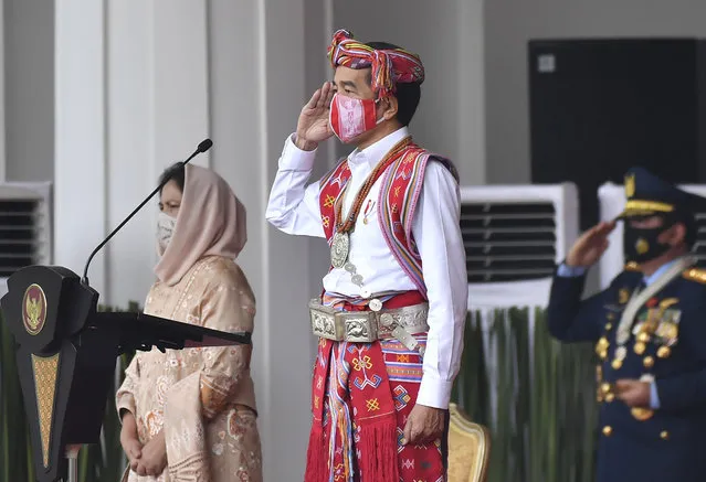 In this photo released by Indonesian Presidential Palace, Indonesian President Joko Widodo, dressed in traditional dress and wearing a face mask as a precaution against the coronavirus, salutes as his wife Iriana, left, looks on, during a flag hoisting ceremony commemorating the country's 75th Independence Day at Merdeka Palace in Jakarta, Indonesia, Monday, August 17. 2020. Indonesia gained its independence from the Dutch colonial rule in 1945. (Photo by Agus Suparto, Presidential Palace via AP Photo)