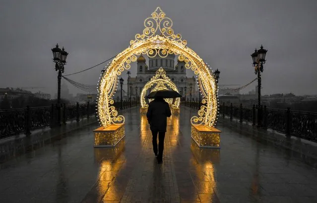 A pedestrian holds an umbrella as he walks past Christmas decorations during rainy weather near the Cathedral of Christ the Saviour in central Moscow on December 13, 2022. (Photo by Yuri Kadobnov/AFP Photo)