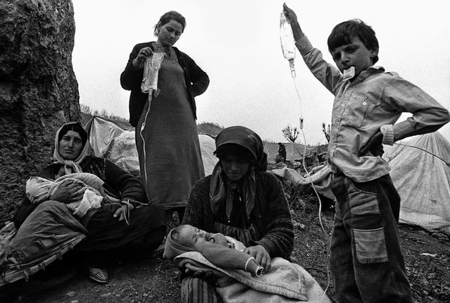 Iraqi Kurdish refugees wait with children in Cukurca refugee camp in Turkey April 8, 1991. Reuters photographers have chronicled Kurdish refugee crises over the years. In 1991 Srdjan Zivulovic documented refugees in Cukurca who had escaped a military operation by Saddam Hussein's government in Iraq aimed at “Arabising” Kurdish areas in the north. (Photo by Srdjan Zivulovic/Reuters)