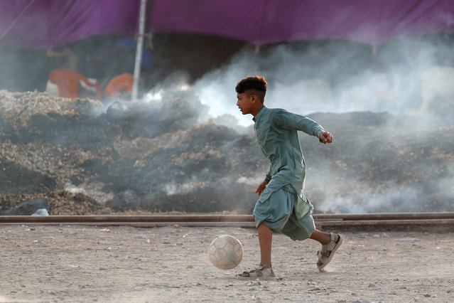 A boy plays with a soccer ball next to a smouldering pile of rubbish, ahead of the World Environment Day, in Karachi, Pakistan, on June 4, 2025. (Photo by Akhtar Soomro/Reuters)