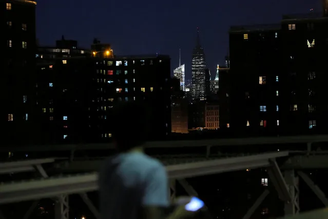 A person on the Brooklyn Bridge looks on as the spire of the Empire State Building remains unlit in honor of the victims of the Nice attacks in Manhattan, New York, U.S., July 15, 2016. (Photo by Andrew Kelly/Reuters)
