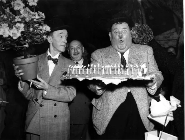 Comedian Stan Laurel, left, looks on as Oliver Hardy gets ready to blow out the candles on his birthday cake in Billancourt, France, on January 18, 1951.  Hardy is celebrating his 58th birthday. The man at center is not identified. (Photo by AP Photo)