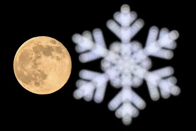 This photograph shows the full moon also known as Wolf moon behind a Christmas and New Year's decoration in Moscow on January 7, 2023. (Photo by Kirill Kudryavtsev/AFP Photo)