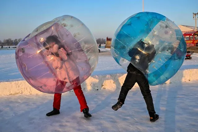 Children play inside plastic balls at an amusement park in Harbin, in China's northeastern Heilongjiang province, on January 4, 2023, ahead of the 39th Harbin China International Ice and Snow Festival. (Photo by Hector Retamal/AFP Photo)