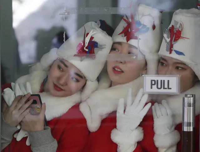 The women who hand out the awards for the winners ceremony watch the sliders during the men's skeleton final at the 2018 Winter Olympics in Pyeongchang, South Korea, Friday, February 16, 2018. (Photo by Michael Sohn/AP Photo)
