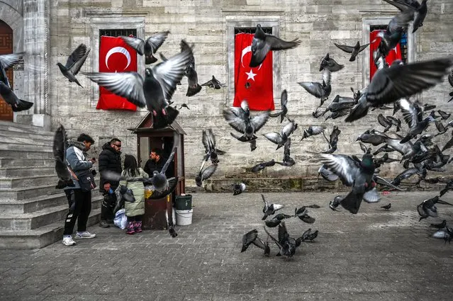 Pigeons fly in front of the New Mosque in the Eminonu district in Istanbul, on January 10, 2023. (Photo by Ozan Kose/AFP Photo)