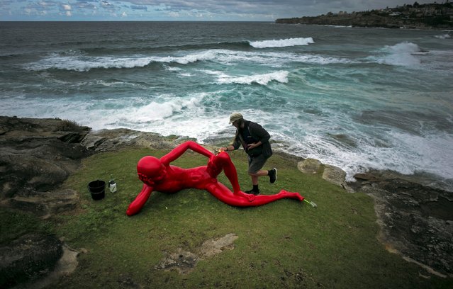 A volunteer wipes sea spray off the painted bronze sculpture entitled 'Harbour' by Chinese artist Chen Wenling during the 19th annual Sculptures by the Sea exhibition in Sydney, October 23, 2015. (Photo by Jason Reed/Reuters)