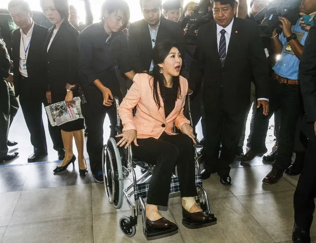 Thailand's Prime Minister Yingluck Shinawatra (C) arrives in a wheelchair at the Royal Police Cadet Academy in Nakorn Pathom province, in this March 18, 2014 file photo. (Photo by Athit Perawongmetha/Reuters)