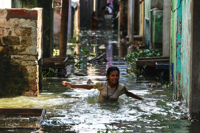A girl wades through a flooded residential area after the water level of the Varuna River rose again due to upstream impact in Varanasi on August 27, 2025. (Photo by Niharika Kulkarni/AFP Photo)