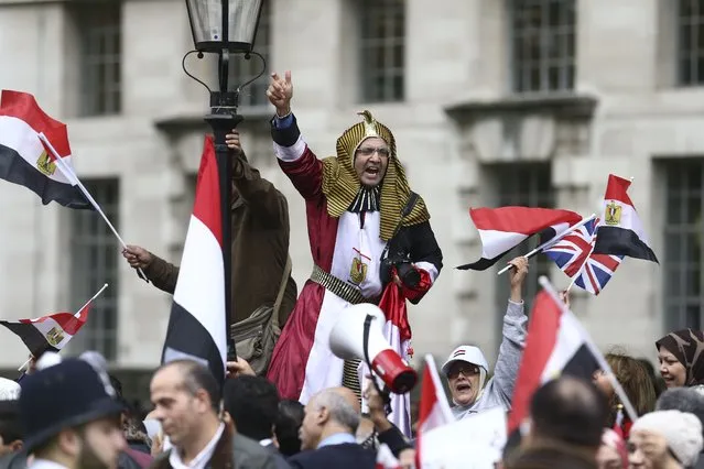 A supporter welcoming the expected visit of Egyptian President Abdel Fattah al-Sisi dressed in a pharaonic costume joins others waving Egyptian and Union flags outside Downing Street in central London on November 5, 2015. (Photo by Justin Tallis/AFP Photo)