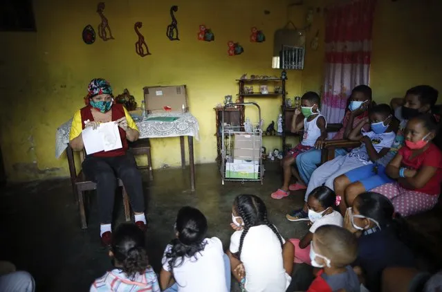 Rosa Carrera tells children a story during an event run by the Venezuelan charity, “Feed the Solidarity”, in the San Agustin neighborhood of Caracas, Venezuela, Wednesday, November 3, 2020. Pandemic lockdowns, teacher shortages and electricity outages are forcing many Venezuelan students to advance their education outside the traditional brick and mortar school setting. (Photo by Ariana Cubillos/AP Photo)