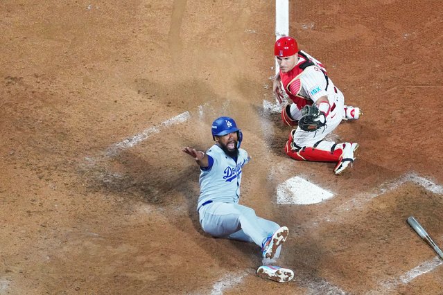 Los Angeles Dodgers' Teoscar Hernandez, left, slides home past Philadelphia Phillies catcher J.T. Realmuto to score off a fielder's choice off of a ground ball hit by Kiké Hernández during the seventh inning in Game 2 of baseball's National League Division Series, Monday, October 6, 2025, in Philadelphia. (Photo by Matt Slocum/AP Photo)