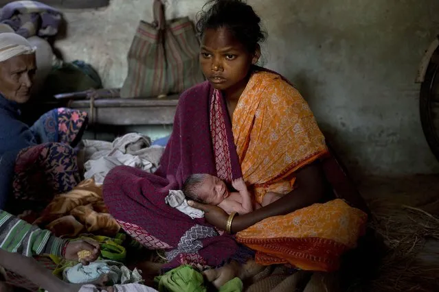Luky Moni Orang, 22, an Indian tribal settler, holds her three-day old baby as she takes refuge in a local church after her village was attacked by an indigenous separatist group, in Shamukjuli village in Sonitpur district of Indian eastern state of Assam, Thursday, December 25, 2014. (Photo by Anupam Nath/AP Photo)
