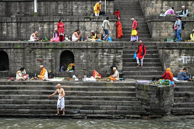 Hindu devotees perform rituals on the banks of the Bagmati River near the Pashupatinath Temple in Kathmandu on September 14, 2025. The capital Kathmandu took a step back towards normality on September 13 as a curfew was eased and daily life returned, with markets opening, traffic returning and families visiting temples. (Photo by Arun Sankar/AFP Photo)