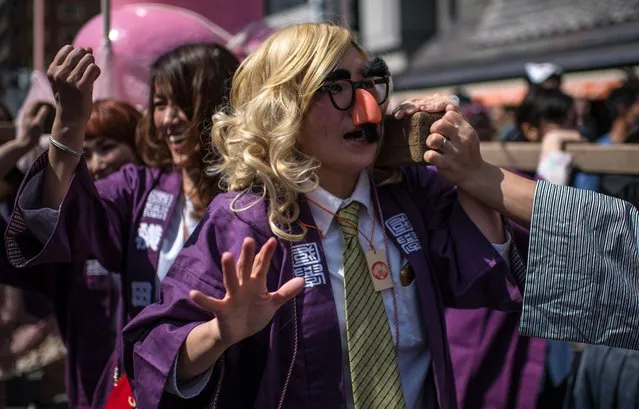 A woman wears a novelty nose and glasses as she helps carry a large pink phallic-shaped “Mikoshi” through the streets during Kanamara Matsuri (Festival of the Steel Phallus) on April 1, 2018 in Kawasaki, Japan. (Photo by Carl Court/Getty Images)