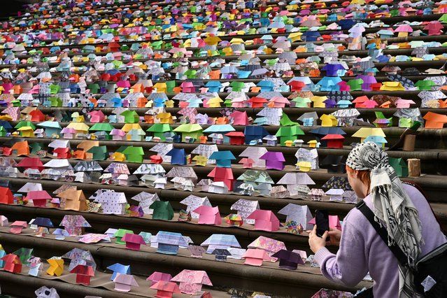 A person takes a photograph of origami houses placed onto the steps of the State Parliament of Victoria in Melbourne, Australia, 31 July 2024. Origami houses were placed on the steps of Victorian Parliament by demonstrators calling for action on social housing shortages. (Photo by James Ross/EPA/EFE)