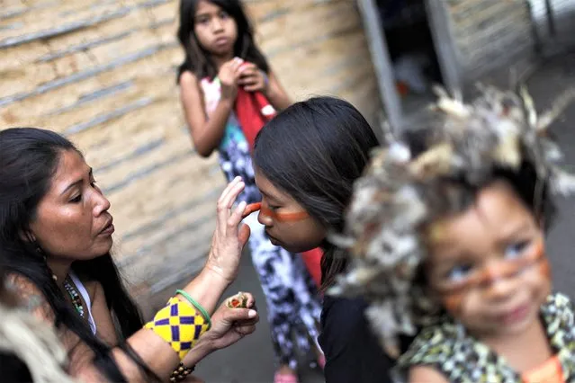 An Indigenous woman from the Guarani Mbya ethnic group paints the face of a kid, during celebrations of Indigenous People Day in Mata Verde Bonita village in Marica near Rio de Janeiro, Brazil on April 19, 2023. (Photo by Ricardo Moraes/Reuters)