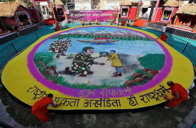 Hindu priests put the finishing touches to a rangoli, or mural made out of coloured powders, at a temple ahead of Diwali, the festival of lights, celebrations in Ahmedabad, India, October 27, 2016. (Photo by Amit Dave/Reuters)