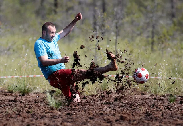 A soccer enthusiast kicks a ball while competing in the Swamp Football Cup of Russia in the village of Pogi in Leningrad Region, Russia June 16, 2018. (Photo by Anton Vaganov/Reuters)