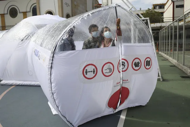 Designers stand inside one of their Portable Epidemiological Insulation Unit during a media presentation, in Bogota, Colombia, Tuesday, February 16, 2021. Colombia’s La Salle University school of architecture designed the small polyhedral pneumatic geodesic domes which can be used to isolate and treat COVID-19 patients in areas where there are no nearby hospitals or where existing hospitals are overwhelmed with patients. (Photo by Fernando Vergara/AP Photo)