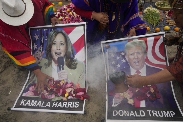 Shamans perform a good luck ritual holding posters of Democratic presidential nominee Vice President Kamala Harris and Republican presidential nominee former President Donald Trump, at the beach in Lima, Peru, Tuesday, November 5, 2024. (Photo by Martin Mejia/AP Photo)