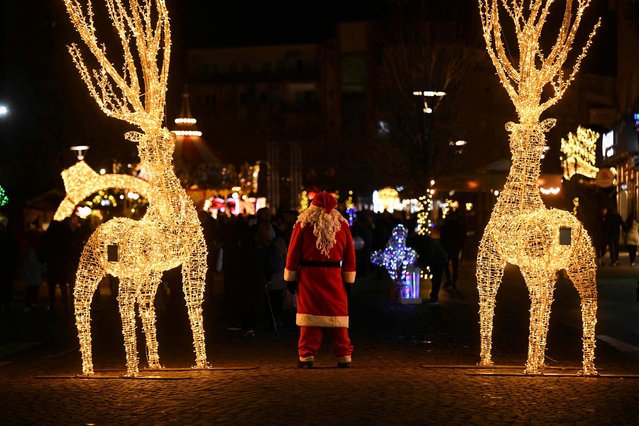 A man dressed as Santa Claus stands in front of decorations in the Christmas market in Pristina on December 21, 2024. (Photo by Armend Nimani/AFP Photo)