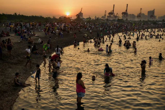 Filipino families flock to a makeshift beach in the polluted waters of Manila bay, to escape the summer heat on March 7, 2021 in Manila, Philippines. A makeshift beach in Manilas slum village of Baseco was opened to the public as the country enters the summer season in the month of March. As public gathering restrictions are still in place due to the Coronavirus pandemic, the beach is only open for two hours in the early morning every Sunday. (Photo by Jes Aznar/Getty Images)