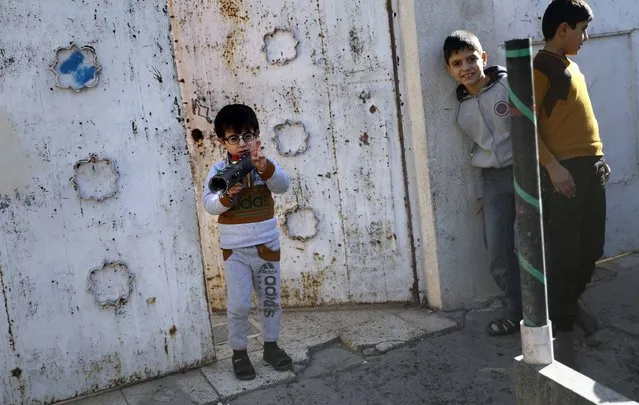 An Iraqi boy plays with a homemade Rocket-propelled grenade (RPG) toy in a northeastern district of the city of Mosul on November 24, 2016. While aid agencies estimated that some 200,000 residents could flee the city in the first weeks of the fighting, five weeks into the operation only around 70,000 civilians have fled their homes. Those who stay behind in the city – often too scared or unable to quit – are facing both danger and deprivation. (Photo by Thomas Coex/AFP Photo)