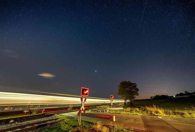 Stars shine on a train passing a railroad crossing in Wehrheim near Frankfurt, Germany, Tuesday, September 20, 2022. (Photo by Michael Probst/AP Photo)