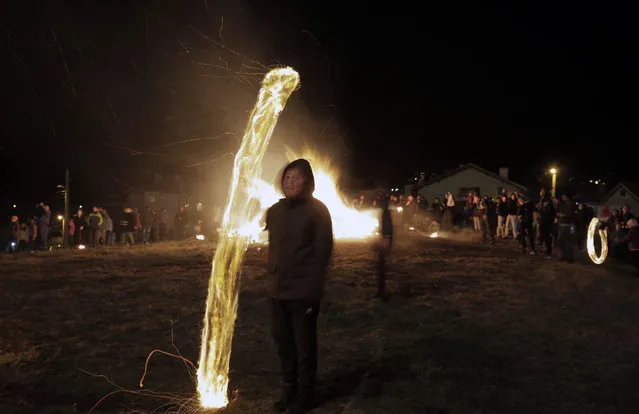 A long exposure photo shows a child who spins a ball of fire near a bonfire during rituals in celebration of Mesni Zagovezni (Shrovetide) in the village of Lozen near the capital Sofia, Sunday, March 14, 2021. People in the region believe they can chase away evil spirits by performing fire rituals on Mesni Zagovezni. (Photo by Valentina Petrova/AP Photo)