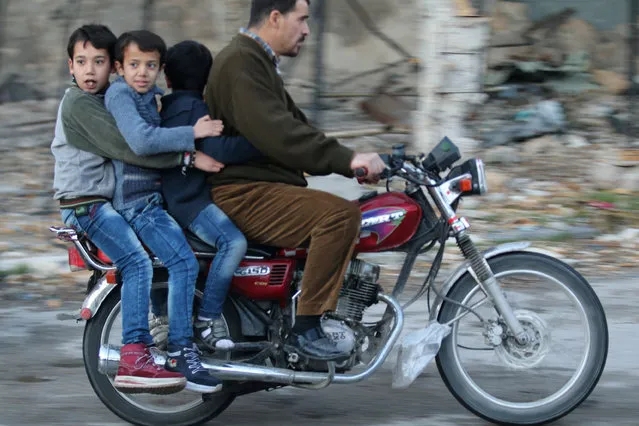 Boys ride a motorcycle with a man in rebel-held besieged old Aleppo, Syria December 2, 2016. (Photo by Abdalrhman Ismail/Reuters)