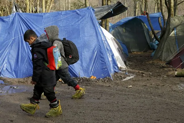 Migrant children make their way past shelters in a muddy field called the Grande-Synthe jungle, near Dunkirk, northern France, January 12, 2016. (Photo by Benoit Tessier/Reuters)