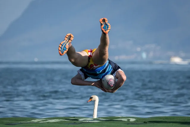 This picture taken on September 2, 2023 shows a player scoring a try by jumping into Lake Geneva next to a swan from a floating rugby field during the Water Rugby Lausanne, a three-day tournament organized by the LUC Rugby that gathered more than 240 players in Lausanne, western Switzerland. (Photo by Fabrice Coffrini/AFP Photo)
