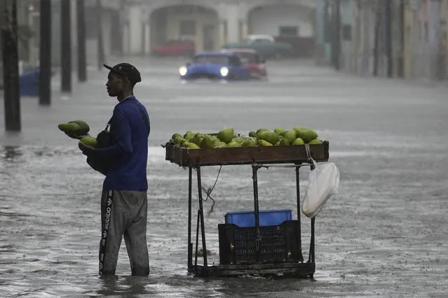 An avocado vender works in a street flooded by rain brought by Hurricane Idalia in Havana, Cuba, early Tuesday, August 29, 2023. (Photo by Ramon Espinosa/AP Photo)