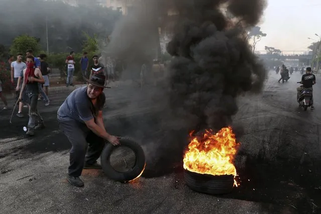 Protesters burn tires to block a road, in Beirut, Lebanon, Thursday, June 24, 2021. Dozens of angry protesters, angered by deteriorating living conditions and government inaction, partially blocked Beirut's main highway to the capital's only airport, turning trash bin over and setting tires on fire. (Photo by Bilal Hussein/AP Photo)