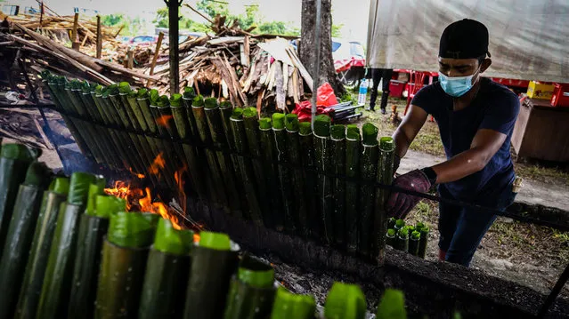 A man prepares traditional dish “lemang” ahead of the upcoming Eid al-Fitr in Kuala Lumpur, Malaysia on May 08, 2021. The traditional dish lemang, made by cooking the rice placed in bamboo canes over a wood fire, is cooked and sold in tents set up on the side of the road a week before the Eid al-Fitr. (Photo by Syaiful Redzuan/Anadolu Agency via Getty Images)